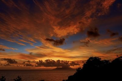 Scenic view of sea against dramatic sky during sunset