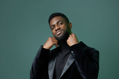 Portrait of young man standing against black background