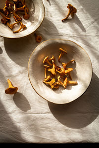 High angle of chanterelle mushroom on bowl placed on table at sunlight in countryside home