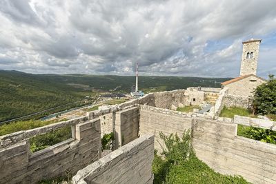 Scenic view of mountains and buildings against cloudy sky