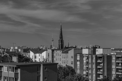 Buildings in city against cloudy sky