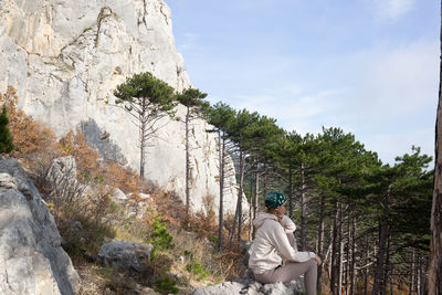 Rear view of man sitting on rock