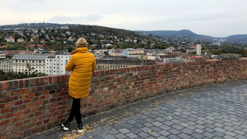 Rear view of woman standing by buildings against sky