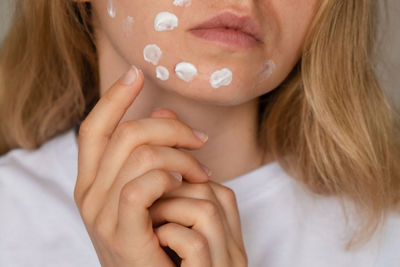 Unrecognizable woman applies makeup, cream serum cure for acne on face. close-up acne on woman's