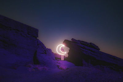Light painting on rock against sky at night