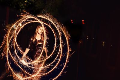 Woman spinning illuminated wire wool at night