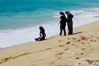 Rear view of friends enjoying at beach