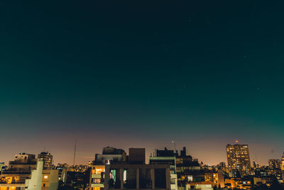 Illuminated buildings against clear sky at night