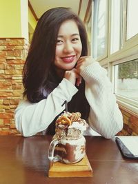 Portrait of smiling young woman sitting at home