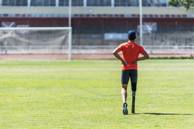 Rear view of woman playing soccer on field