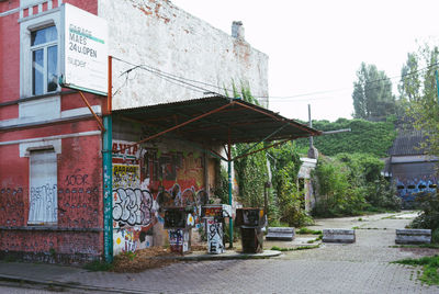 Graffiti on building by street against sky in city