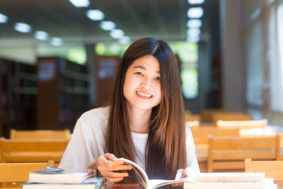 Portrait of beautiful young woman sitting on table