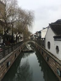 Bridge over canal amidst buildings against sky