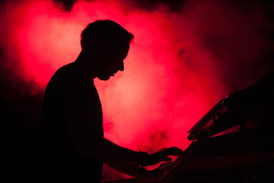 Side view of silhouette man playing piano in music concert
