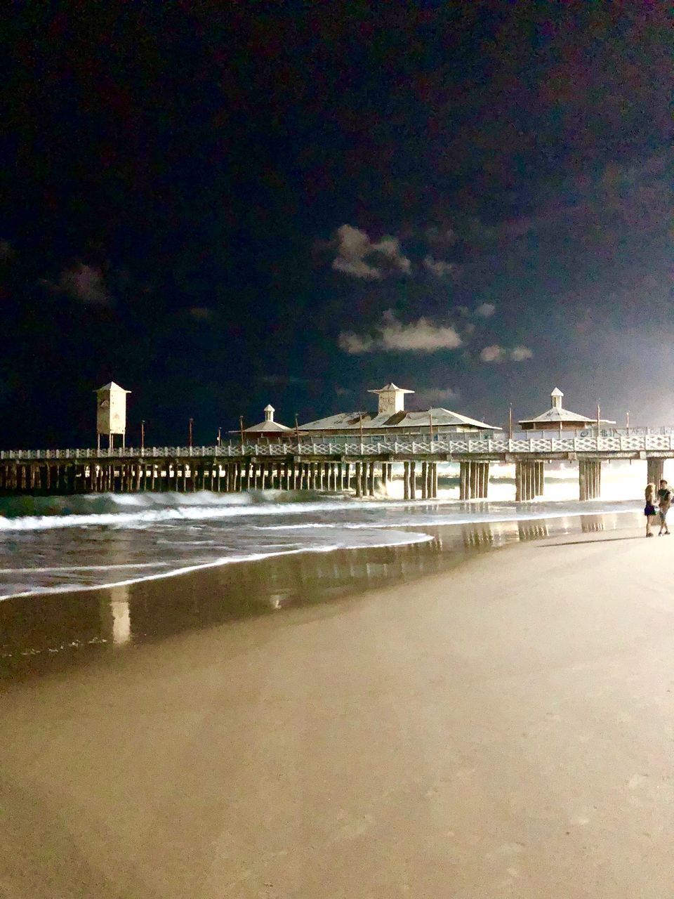 ILLUMINATED BUILDINGS BY SEA AGAINST SKY