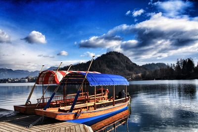 Boat moored on lake against sky