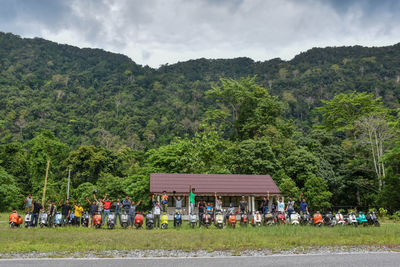 People on street against trees and mountains against sky