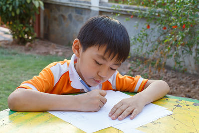 Boy writing on paper at table