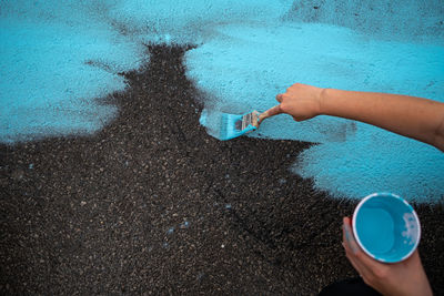 Hand painting blue mural onto city street 