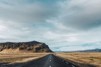 Empty road along landscape against sky