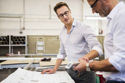 Two businessmen in factory discussing component and plan