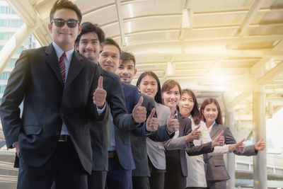 Business colleagues gesturing thumbs up while standing in row