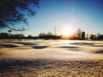 Snow covered field against sky during sunset