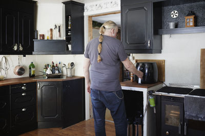 Mature man using air fryer in kitchen