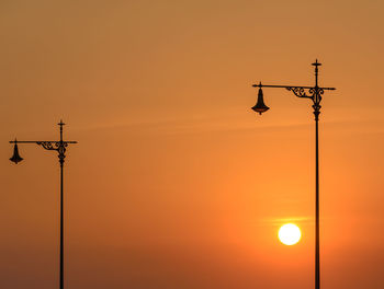 Low angle view of silhouette street light against orange sky