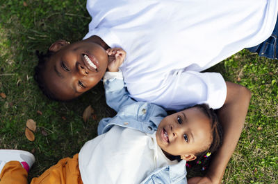 Happy mother with daughter lying on grass at park