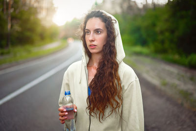 Portrait of young woman standing on road