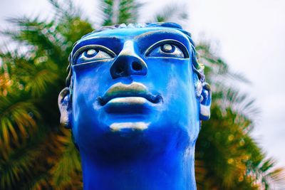 Close-up portrait of sculpture against blue sky