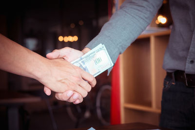 Midsection of couple holding hands at restaurant