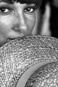 Close-up portrait of woman biting straw hat