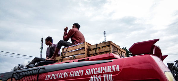 Low angle view of people standing on road against sky