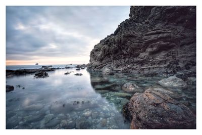 Scenic view of rocks on sea against sky