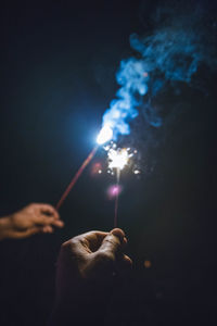 Close-up of hands holding sparklers at night