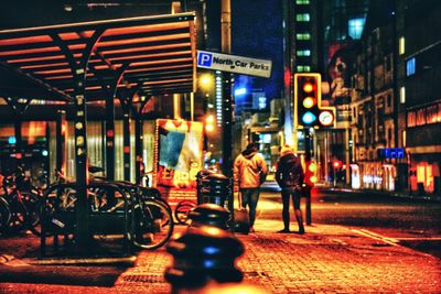 People walking on illuminated city at night