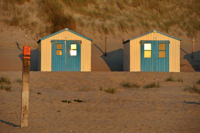 Hut on beach by houses on field