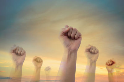 Multiple image of hand with clenched fist against sky during sunset