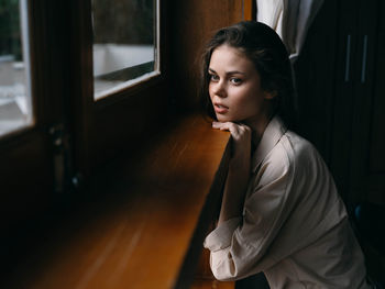 Young woman looking through window