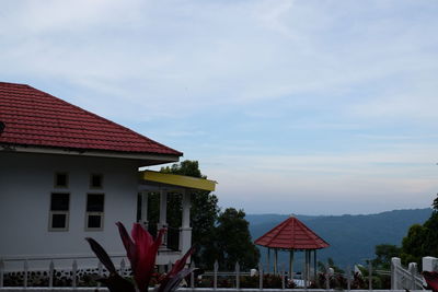 Houses by buildings against sky in city