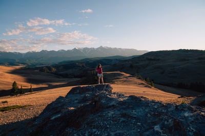 Rear view of woman walking on mountain against sky