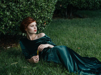 Young woman sitting on grass in field