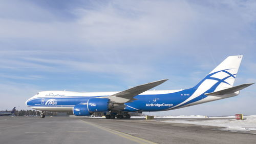 Airplane on airport runway against sky