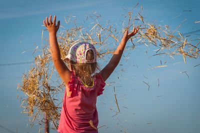 Rear view of a girl throwing up hay