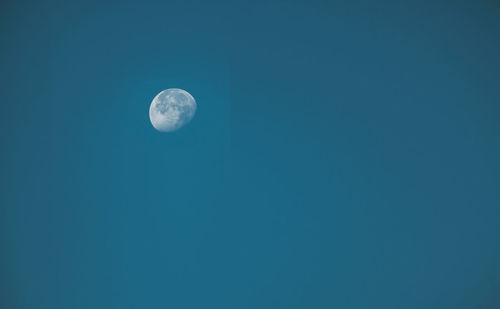 Low angle view of moon against blue sky