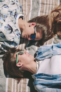 High angle view of friends lying on blanket during sunny day