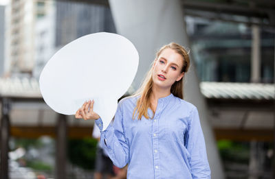 Portrait of young woman standing against built structure