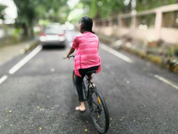 Rear view of woman riding bicycle on road